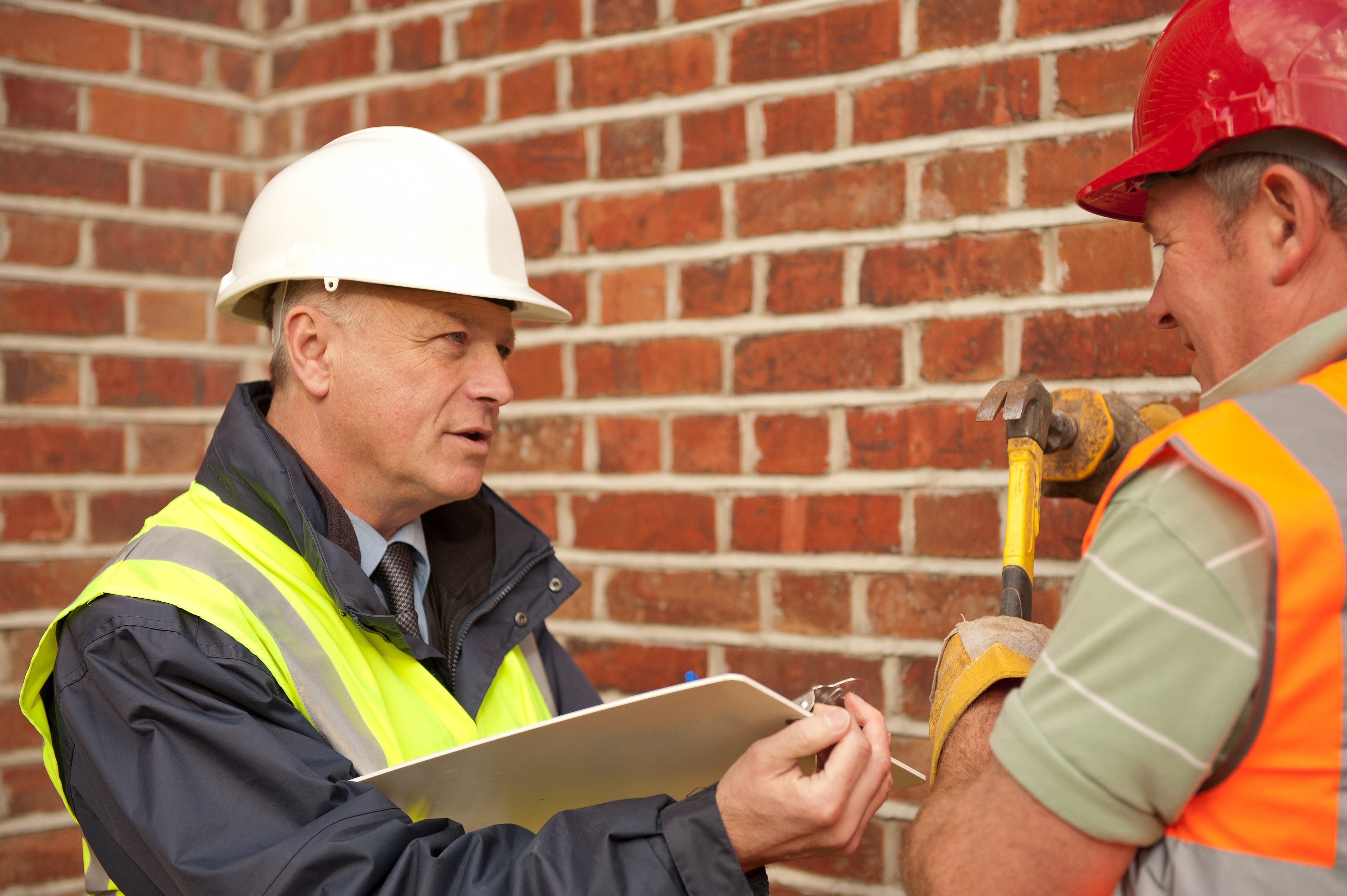 OSHA compliance officer with tablet talking to other worker