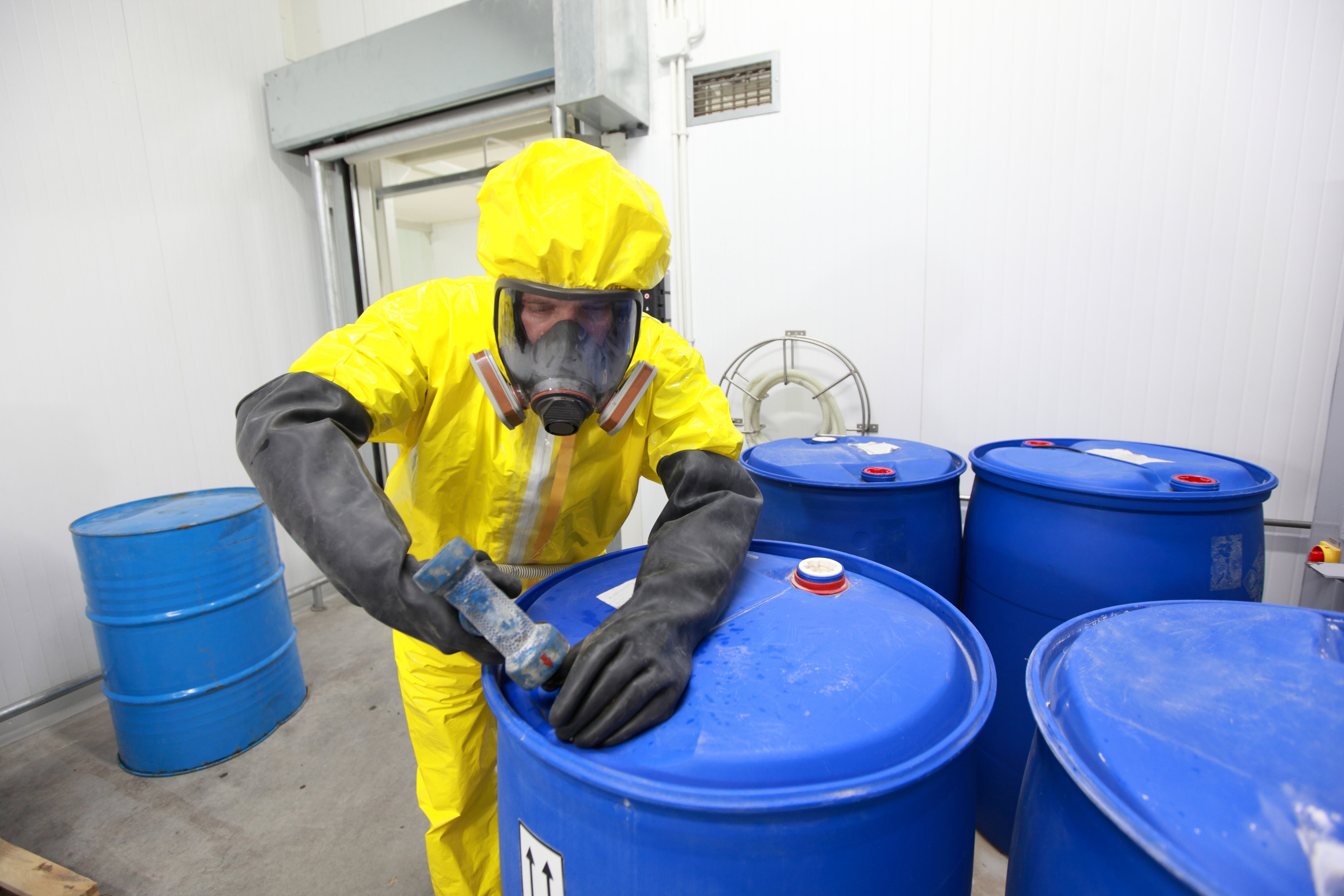 worker in biohazard_hazmat suit with chemical barrels