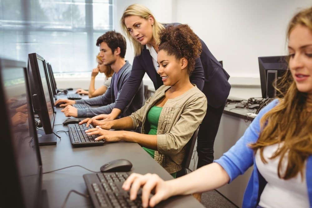 Teacher helping learners in computer room