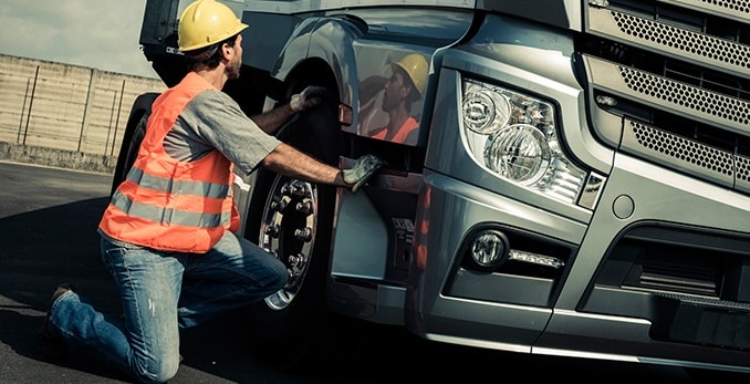 An inspector examining a tire of a truck during a DOT inspection