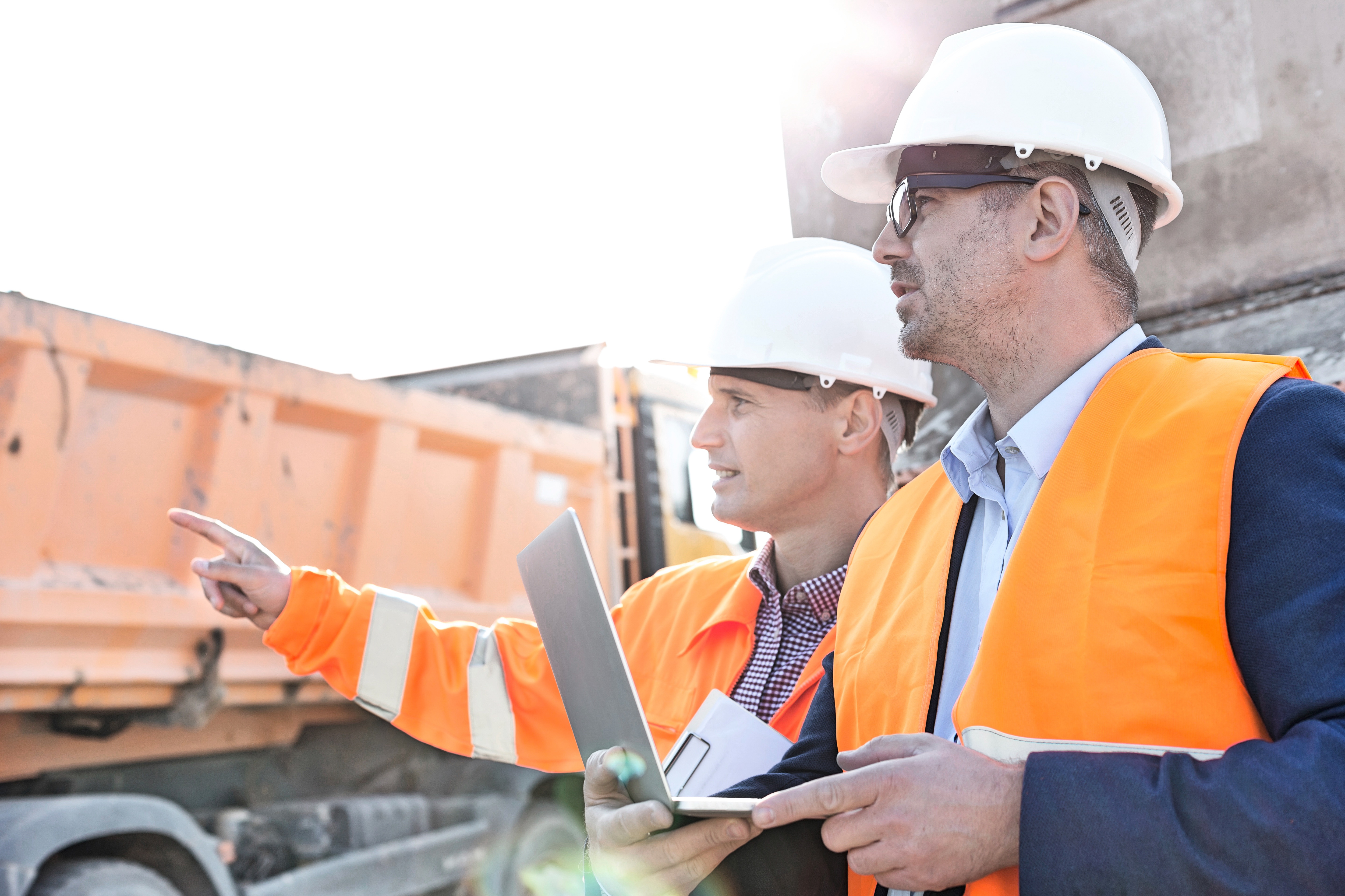 Safety workers in field with laptop, pointing to horizon