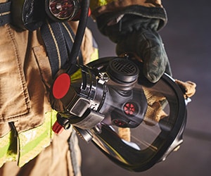 Firefighter holding breathing apparatus. Support firefighter health and wellness with Guardian Tracking.