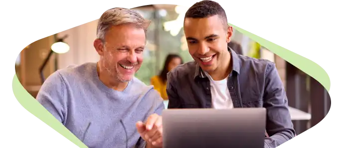 Two workers happily chatting and looking at a laptop