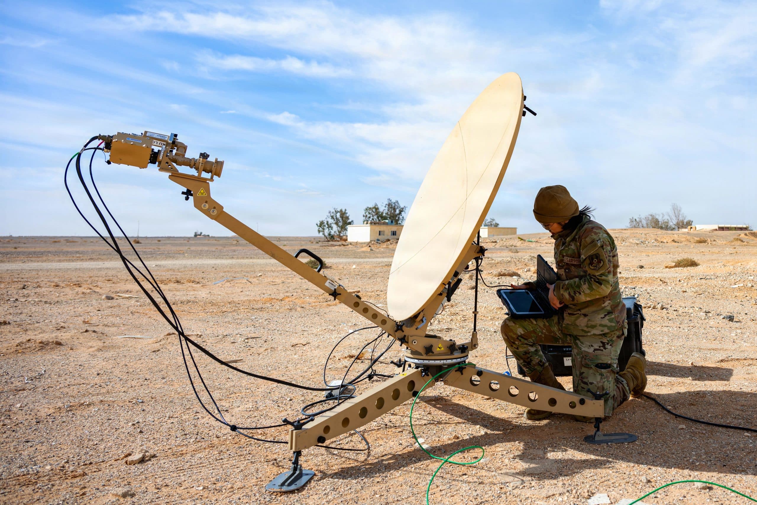 U.S. Air Force airman using a satellite communications system and laptop in a field environment