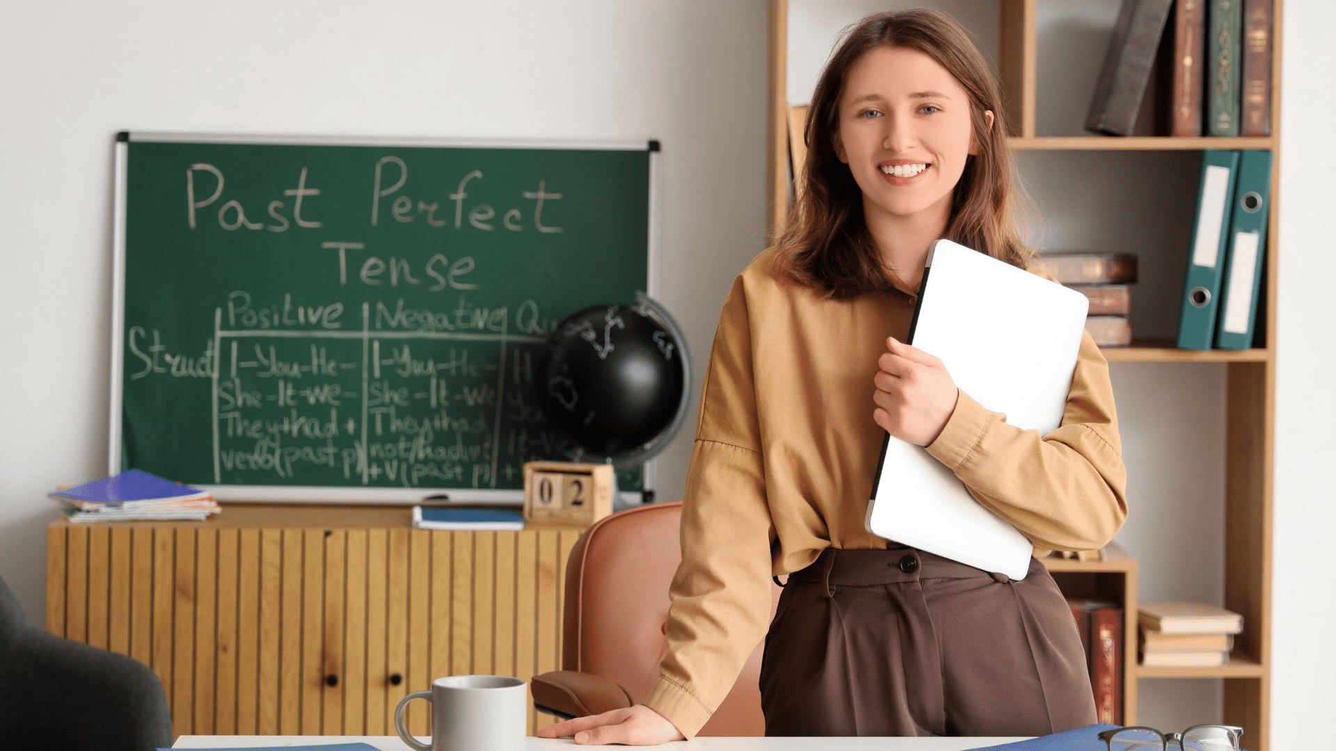 Administrator holding a laptop while standing in a classroom.