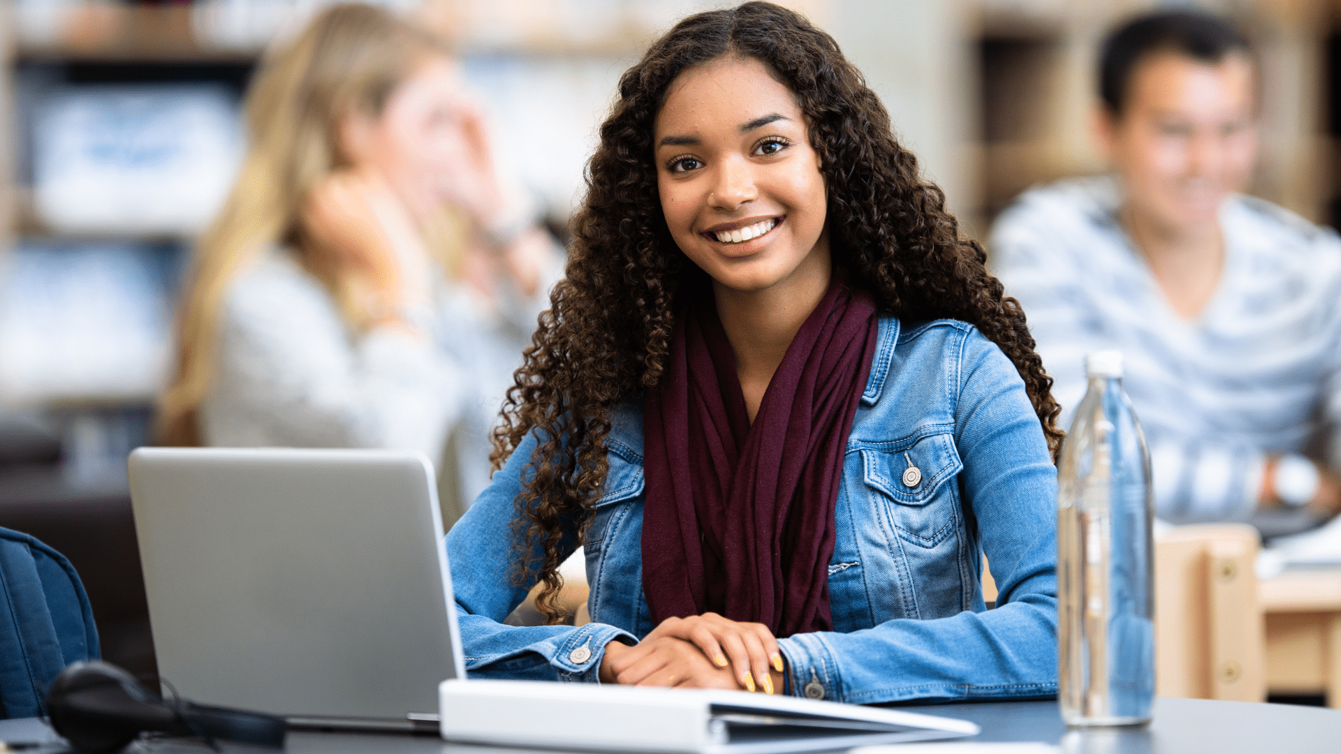 A smiling k-12 student working on a laptop.