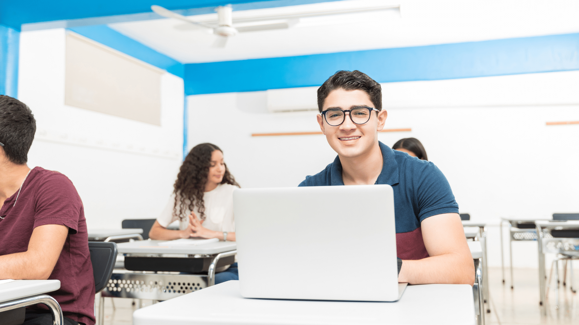 High school student using a laptop while sitting at a desk.